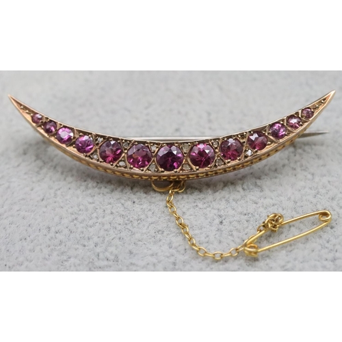 553 - A 9ct gold crescent moon brooch set with 13 graduated purple coloured stones, 5cm long, 3.2 grams gr... 