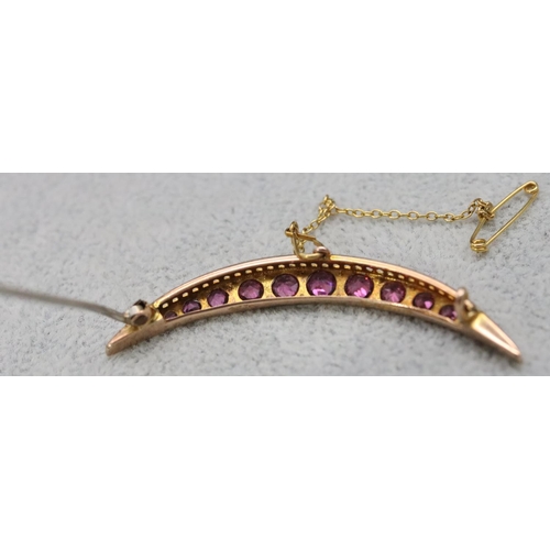 553 - A 9ct gold crescent moon brooch set with 13 graduated purple coloured stones, 5cm long, 3.2 grams gr... 