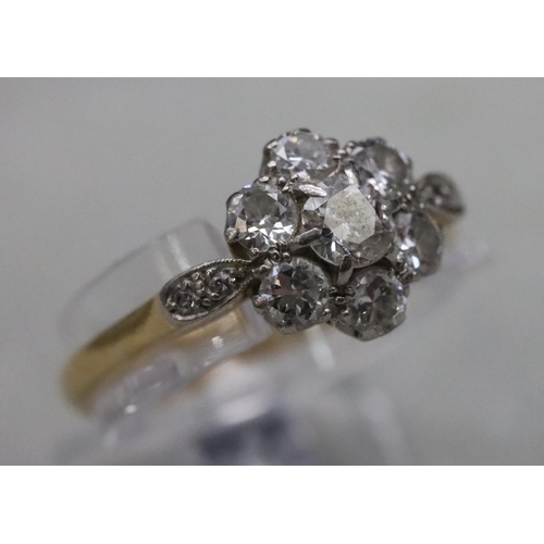 557 - An 18ct gold and platinum ladies' cluster ring set with centre diamond surrounded by 6 small diamond... 