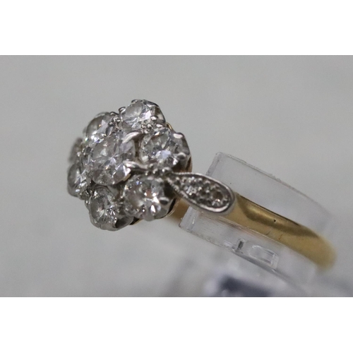 557 - An 18ct gold and platinum ladies' cluster ring set with centre diamond surrounded by 6 small diamond... 