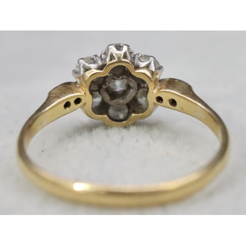 557 - An 18ct gold and platinum ladies' cluster ring set with centre diamond surrounded by 6 small diamond... 