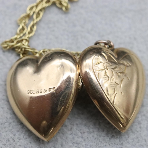 566 - A 9ct gold front and back heart shaped locket with embossed floral motif, mounted on 9ct gold chain ... 