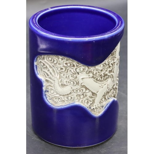 57 - An Oriental cylindrical brush pot on blue ground with inserted white dragon decoration, 14cm high