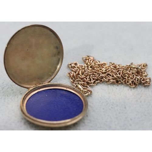 579 - A 9ct gold circular locket with chased hinged lid with scroll decoration, mounted with gold chain, 9... 