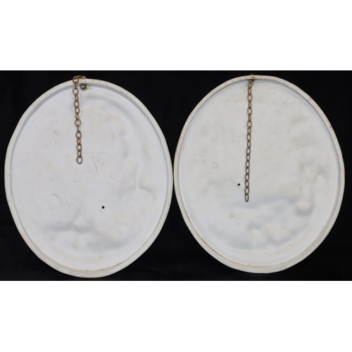 58 - A pair of oval Bisque hanging plaques with raised figures of a seated young gentleman and lady (lady... 