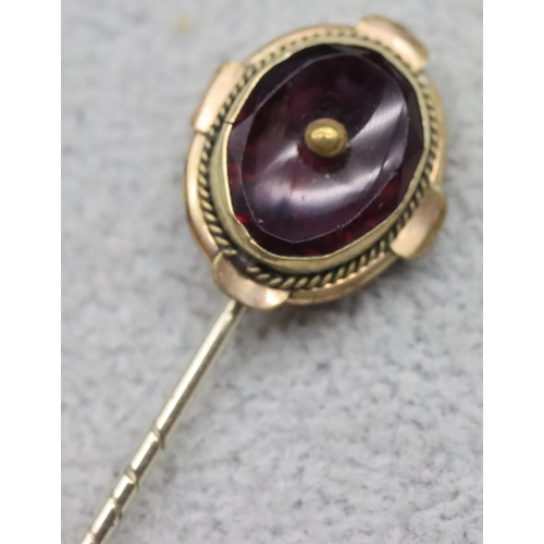 609 - An oval stickpin set with purple stone