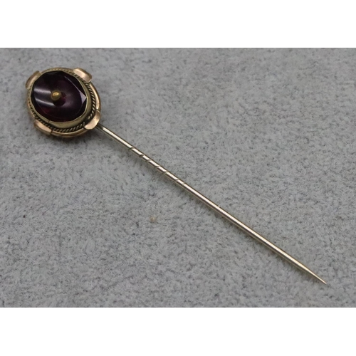 609 - An oval stickpin set with purple stone