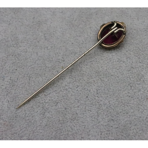 609 - An oval stickpin set with purple stone