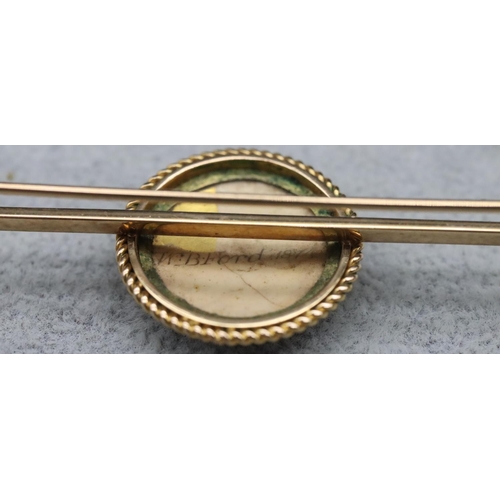 612 - A 9ct gold bar brooch with centre circular china plaque depicting figurehead of a King Charles spani... 