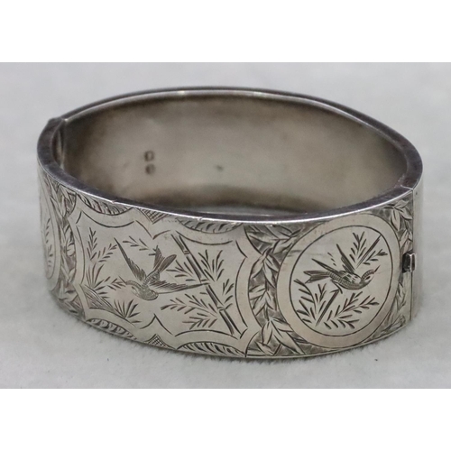 644 - A Birmingham silver wide band hinged bangle with engraved bird, floral and scroll decoration, 24.3 g... 