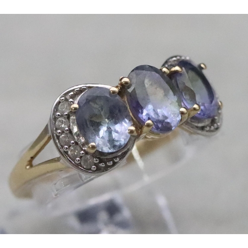 661 - A 9ct gold ladies' 3-stone tanzanite ring surrounded by clear stones, Size Q, 3.2 grams gross