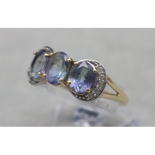 661 - A 9ct gold ladies' 3-stone tanzanite ring surrounded by clear stones, Size Q, 3.2 grams gross