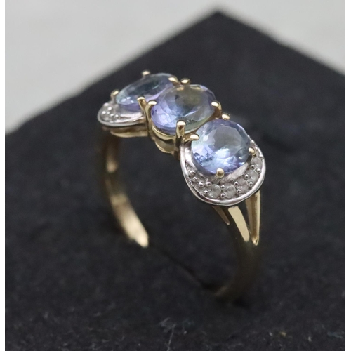 661 - A 9ct gold ladies' 3-stone tanzanite ring surrounded by clear stones, Size Q, 3.2 grams gross