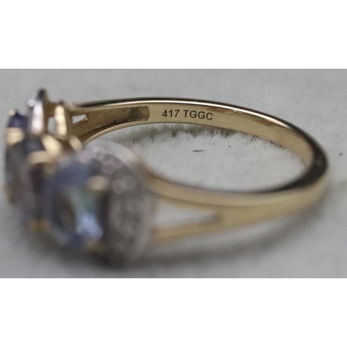 661 - A 9ct gold ladies' 3-stone tanzanite ring surrounded by clear stones, Size Q, 3.2 grams gross