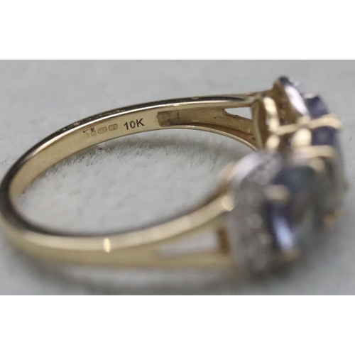 661 - A 9ct gold ladies' 3-stone tanzanite ring surrounded by clear stones, Size Q, 3.2 grams gross