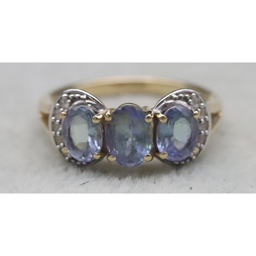 661 - A 9ct gold ladies' 3-stone tanzanite ring surrounded by clear stones, Size Q, 3.2 grams gross