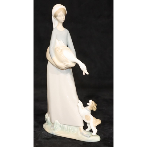 67 - A Lladro group of a young standing lady holding a bird with a puppy at her feet, 27cm high