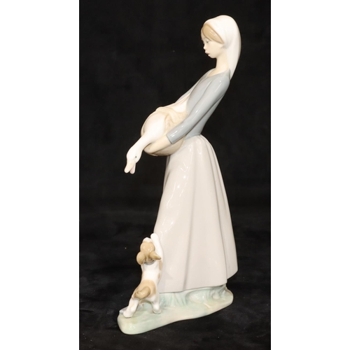 67 - A Lladro group of a young standing lady holding a bird with a puppy at her feet, 27cm high