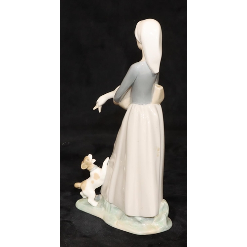 67 - A Lladro group of a young standing lady holding a bird with a puppy at her feet, 27cm high