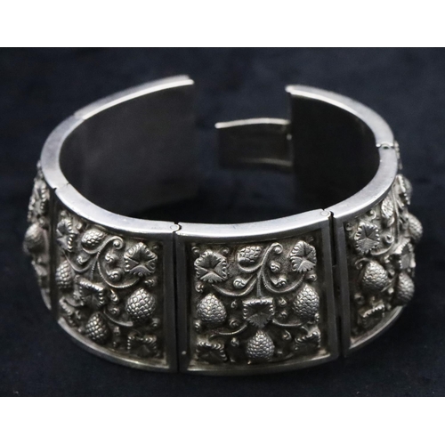 676 - An Eastern silver coloured metal panel bracelet with embossed floral decoration, 96 grams