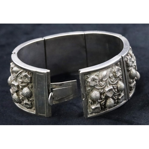 676 - An Eastern silver coloured metal panel bracelet with embossed floral decoration, 96 grams