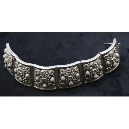 676 - An Eastern silver coloured metal panel bracelet with embossed floral decoration, 96 grams