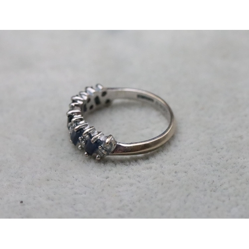 704 - An 18ct white gold ladies' half eternity ring set with baguette sapphires interspersed by small diam... 