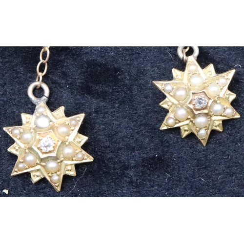 739 - A pair of 18ct gold star shaped drop earrings with centre rough cut diamonds surrounded by half pear... 