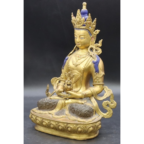 753 - A gilt bronze Eastern figure of a seated female goddess holding an urn with part painted decoration ... 