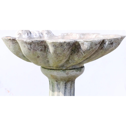 883 - A concrete garden bird bath with shell shaped bowl on round splayed base, 55cm wide, 70cm high