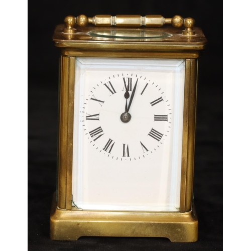 912 - A brass carriage clock with white enamel dial and Roman numerals, swing overhead handle, 11.5cm high... 