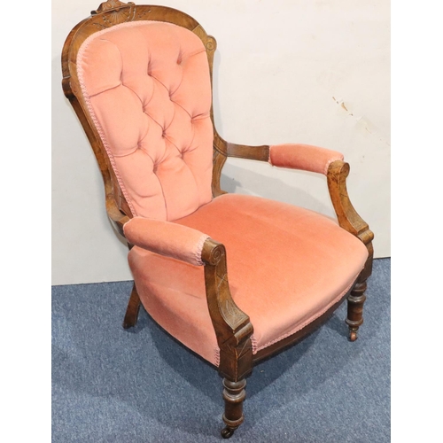 946 - A Victorian walnut armchair with pink velvet overstuffed seat, button back and padded arms.