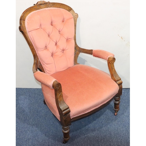 946 - A Victorian walnut armchair with pink velvet overstuffed seat, button back and padded arms.