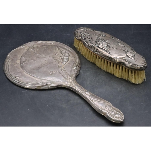 447 - A Birmingham silver hand mirror with embossed floral, leaf and scroll decoration and a matching brus... 