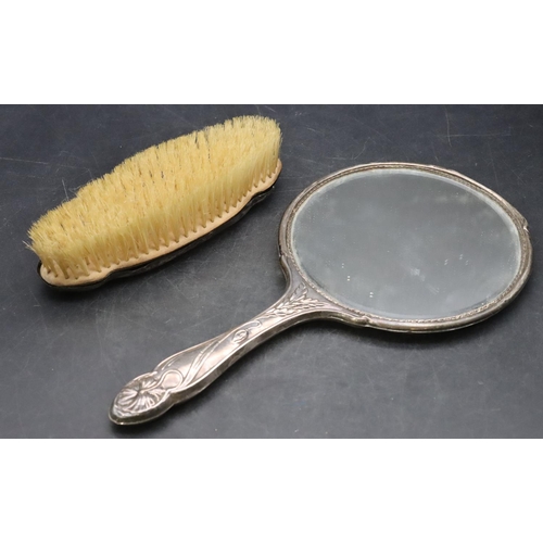 447 - A Birmingham silver hand mirror with embossed floral, leaf and scroll decoration and a matching brus... 