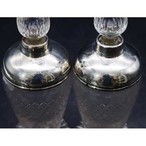 461 - A pair of cut glass round bulbous shaped scent bottles with stoppers and silver shoulders and necks ... 