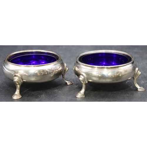 474 - A pair of George III silver round bulbous shaped salts with blue glass liners on splayed hoof feet, ... 