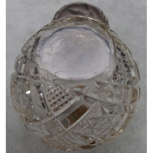 484 - A cut glass round bulbous shaped scent bottle with silver top embossed with leaf and scroll decorati... 