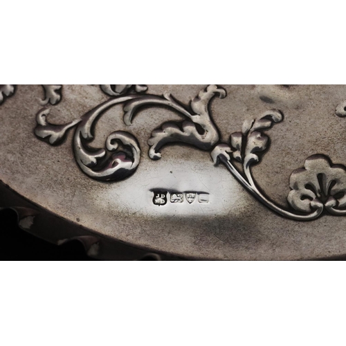 486 - An Edward VII silver scallop shaped dressing table tray with embossed figure, floral and scroll deco... 