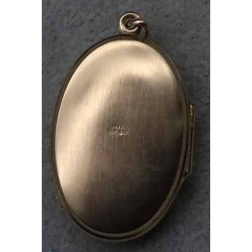 729 - A 9ct gold oval locket with chased scroll hinged front, 5.3 grams gross