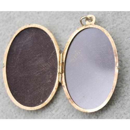 729 - A 9ct gold oval locket with chased scroll hinged front, 5.3 grams gross