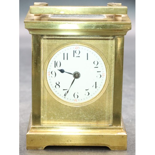 918 - A small brass carriage clock with circular white enamel dial and Arabic numerals, swing overhead han... 