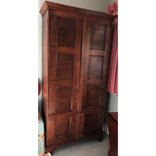 9009 - An oak double cupboard with 2 panel doors, brass lock and key (later sides), enclosing interior uppe... 