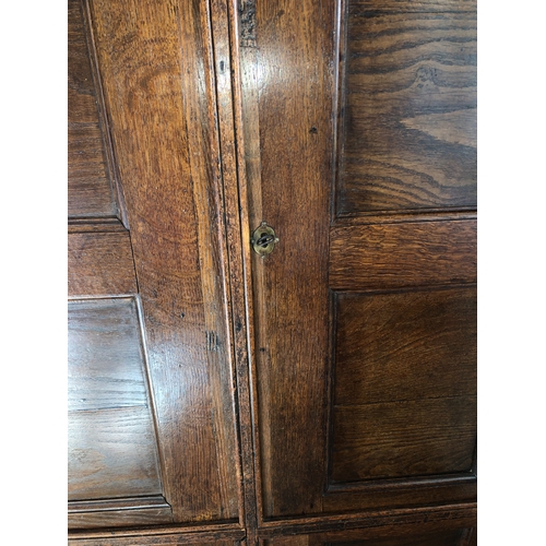 9009 - An oak double cupboard with 2 panel doors, brass lock and key (later sides), enclosing interior uppe... 