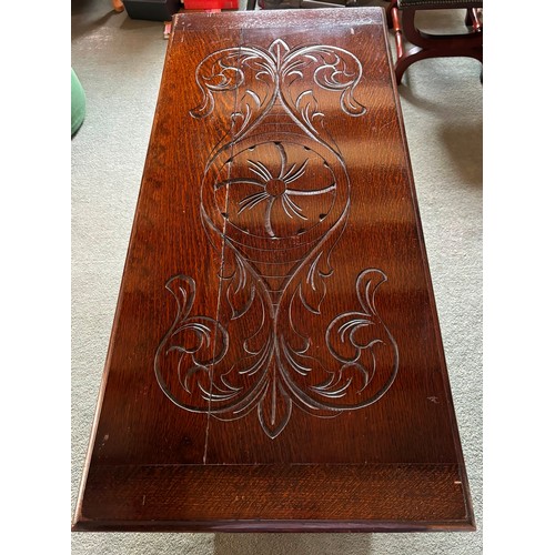 9227 - An oak monk's bench with carved decoration and ornate arms in the style of lions, on square feet.  C... 