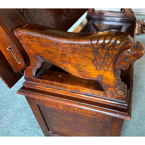 9227 - An oak monk's bench with carved decoration and ornate arms in the style of lions, on square feet.  C... 