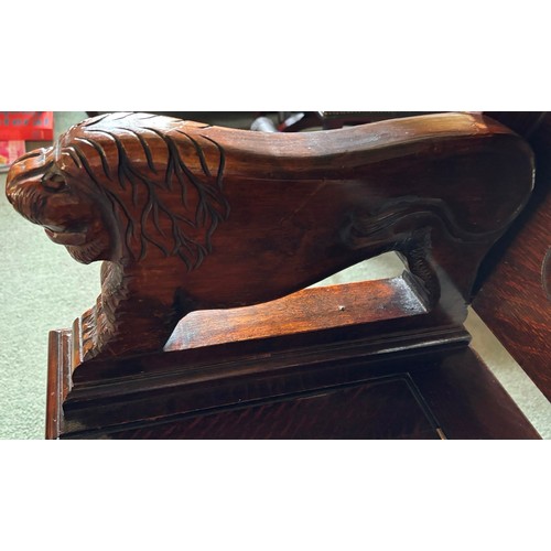 9227 - An oak monk's bench with carved decoration and ornate arms in the style of lions, on square feet.  C... 