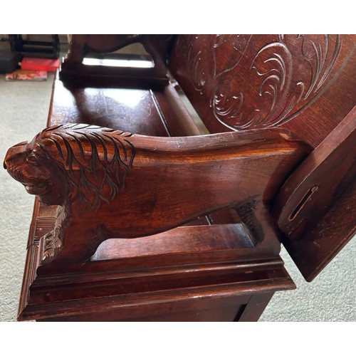 9227 - An oak monk's bench with carved decoration and ornate arms in the style of lions, on square feet.  C... 