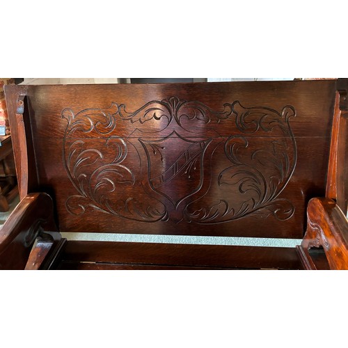 9227 - An oak monk's bench with carved decoration and ornate arms in the style of lions, on square feet.  C... 