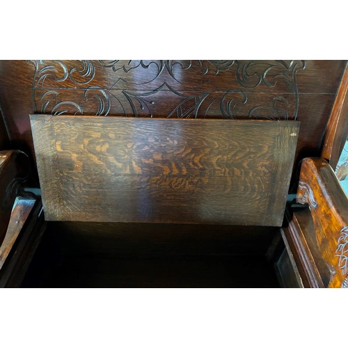 9227 - An oak monk's bench with carved decoration and ornate arms in the style of lions, on square feet.  C... 